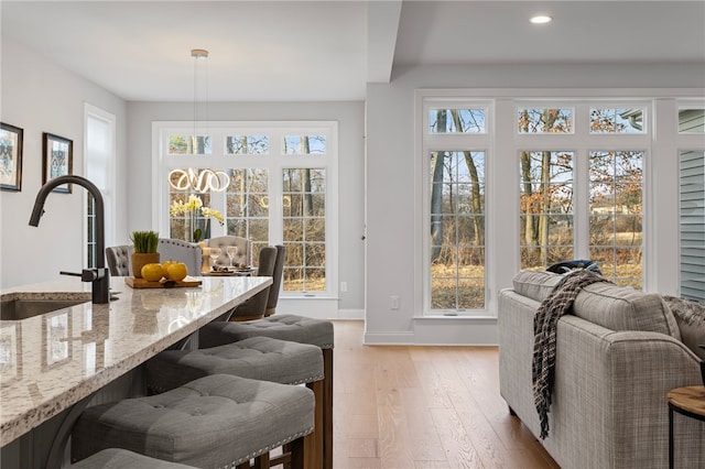 interior space featuring light wood-style flooring, baseboards, a sink, and recessed lighting