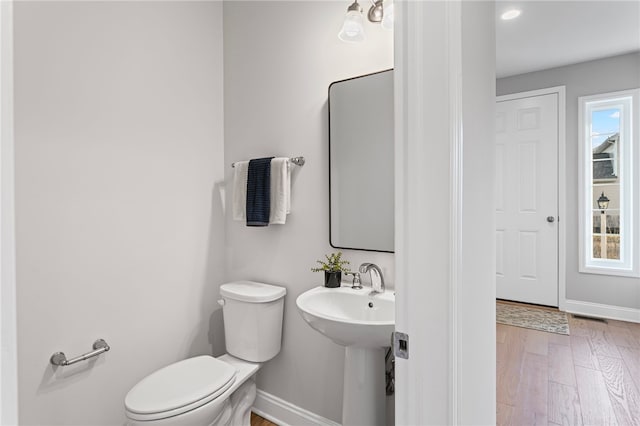 half bath featuring baseboards, toilet, and wood finished floors