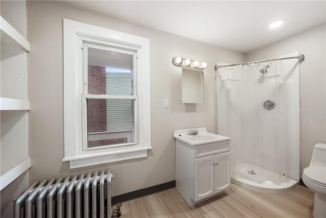 full bathroom with a stall shower, radiator, vanity, and toilet