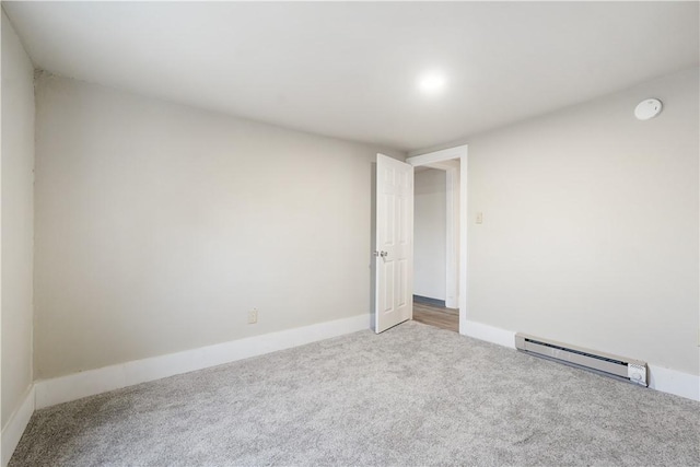 carpeted spare room with a baseboard radiator and baseboards