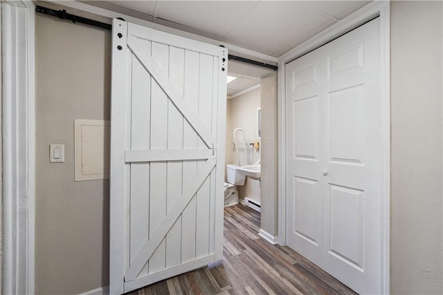 hallway with dark wood-style floors, a barn door, and baseboard heating