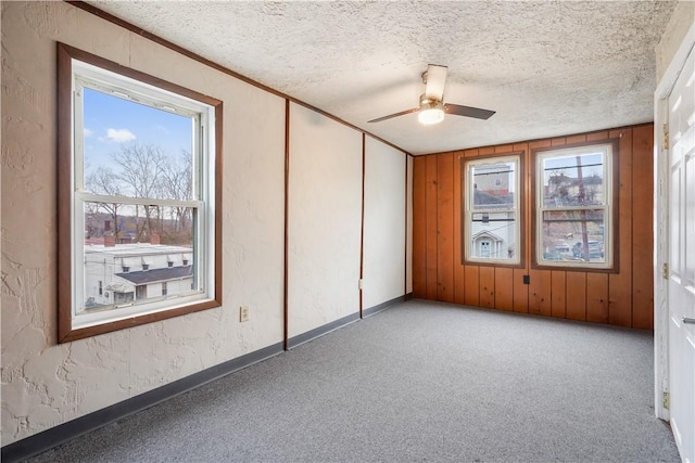 spare room featuring light carpet, ceiling fan, a textured ceiling, and a textured wall