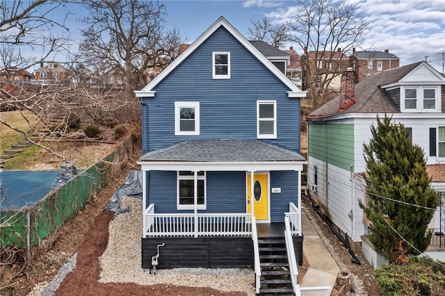 view of front of house with roof with shingles, a porch, and stairway