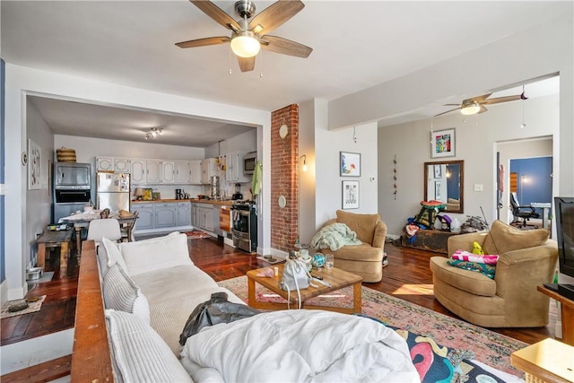 living room with dark wood-style floors, ceiling fan, and baseboards