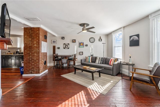 living area featuring dark wood-style floors, visible vents, baseboards, and a ceiling fan