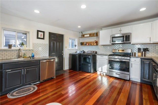 kitchen featuring a sink, stainless steel appliances, washing machine and clothes dryer, and white cabinetry