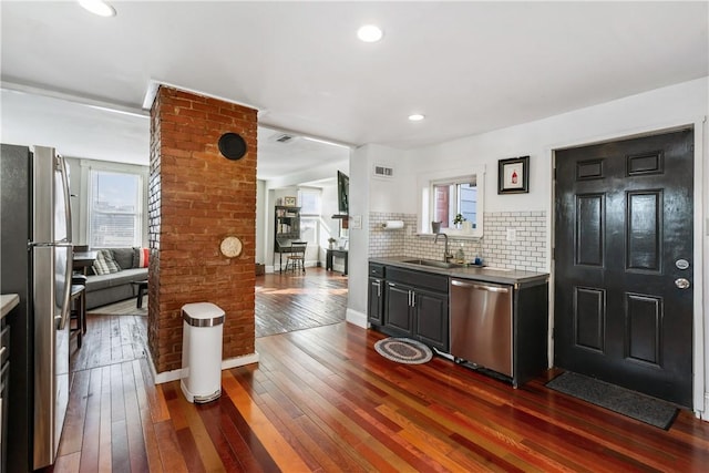 bar with stainless steel appliances, a wealth of natural light, a sink, and dark wood finished floors