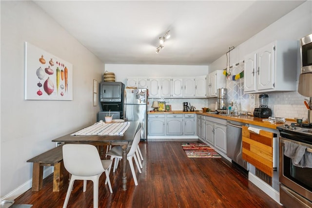 kitchen with appliances with stainless steel finishes, dark wood-style flooring, wood counters, and decorative backsplash