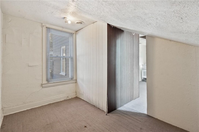 corridor with a textured ceiling, a textured wall, carpet, and visible vents