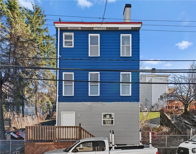 rear view of property with fence and a chimney