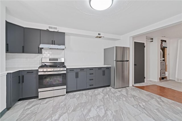 kitchen featuring stainless steel appliances, gray cabinets, light countertops, and under cabinet range hood