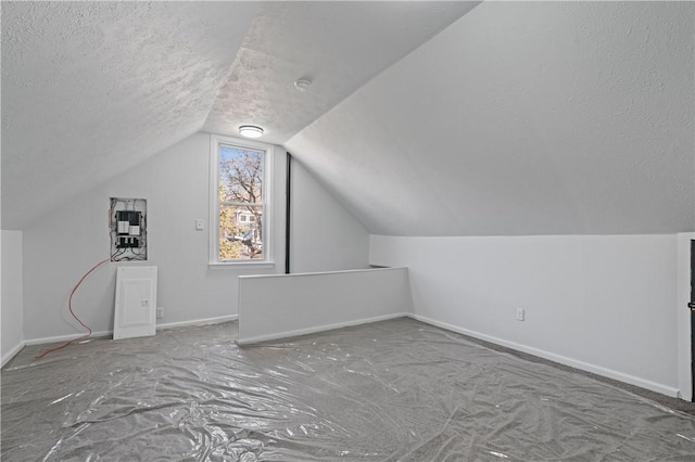 additional living space featuring lofted ceiling, a textured ceiling, and baseboards