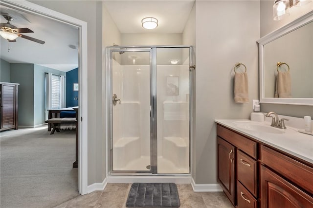 full bath with tile patterned flooring, vanity, baseboards, a ceiling fan, and a stall shower