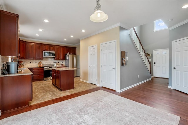 kitchen featuring decorative backsplash, appliances with stainless steel finishes, a center island, light countertops, and light wood-style floors