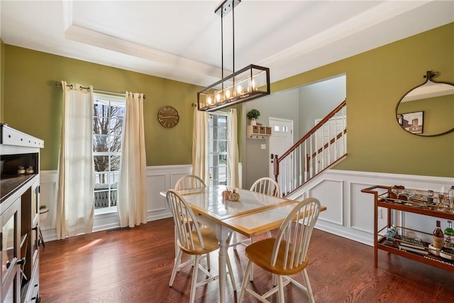 dining room with wainscoting, dark wood finished floors, a decorative wall, and stairs