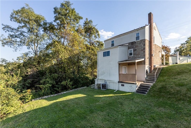 rear view of house featuring a yard, central AC unit, and a chimney