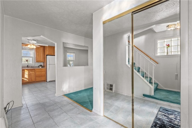 interior space featuring visible vents, ceiling fan, a textured ceiling, and stairs