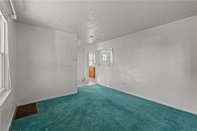 carpeted empty room featuring visible vents and a textured ceiling