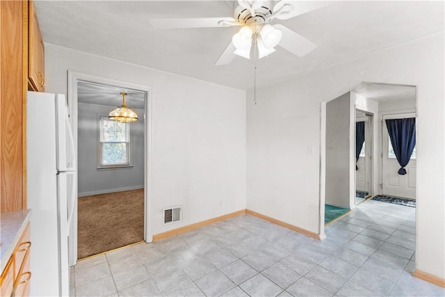 empty room featuring ceiling fan, visible vents, and baseboards