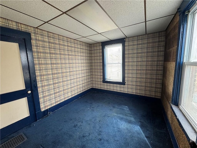 empty room with carpet flooring, visible vents, a drop ceiling, and wallpapered walls