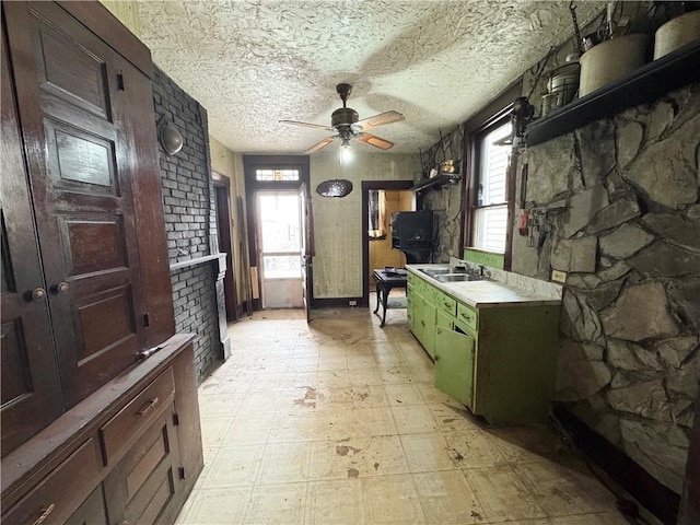 kitchen with light floors, a textured ceiling, light countertops, and a sink