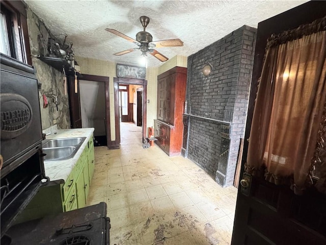 interior space with a ceiling fan, light countertops, a textured ceiling, light floors, and a sink