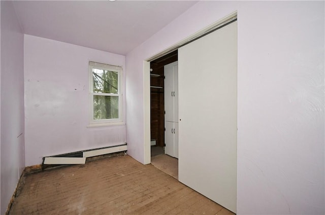 unfurnished bedroom with light wood finished floors and baseboard heating