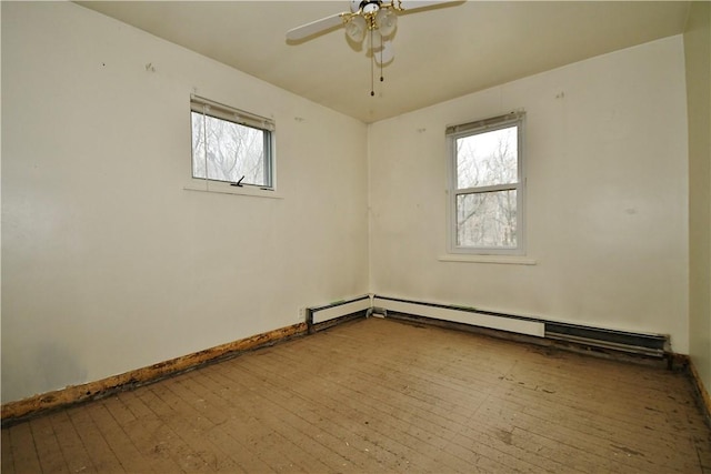 empty room featuring a baseboard heating unit, hardwood / wood-style floors, a ceiling fan, and baseboards