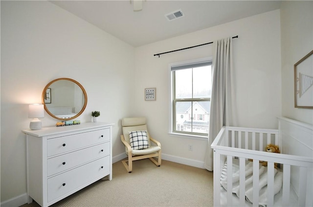 bedroom featuring light carpet, a nursery area, baseboards, and visible vents