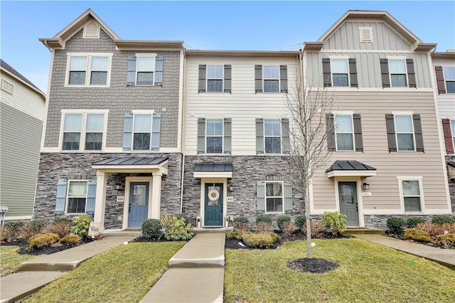 townhome / multi-family property featuring stone siding, board and batten siding, and a front yard