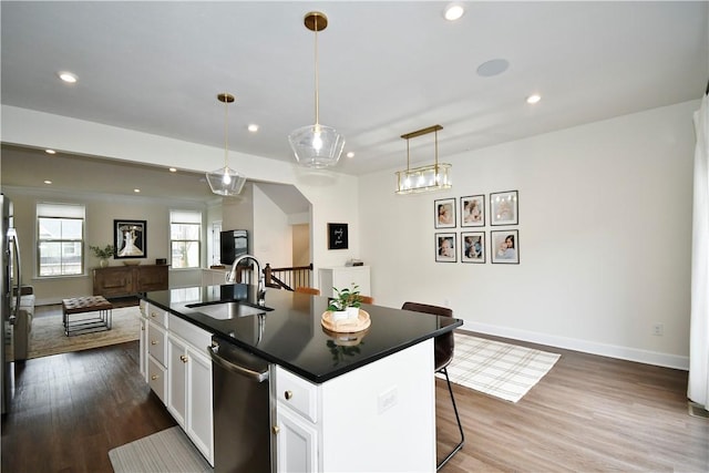 kitchen featuring dark wood-style flooring, dark countertops, open floor plan, white cabinetry, and a sink