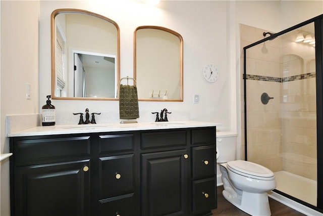 full bathroom featuring double vanity, tiled shower, a sink, and toilet