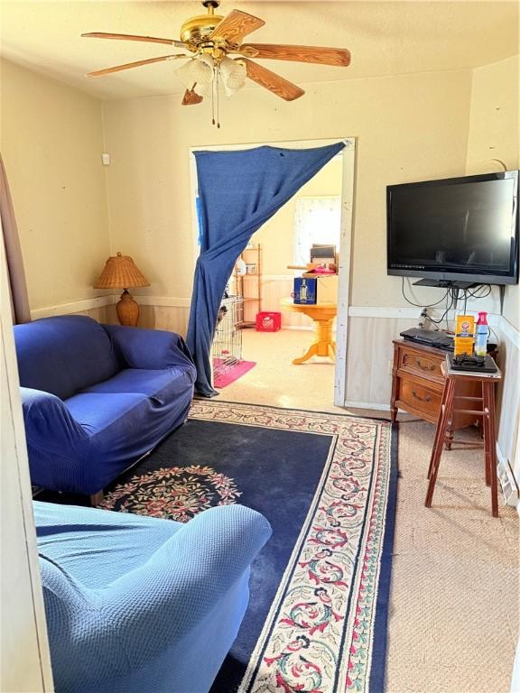 living room with carpet floors, a wainscoted wall, and wooden walls