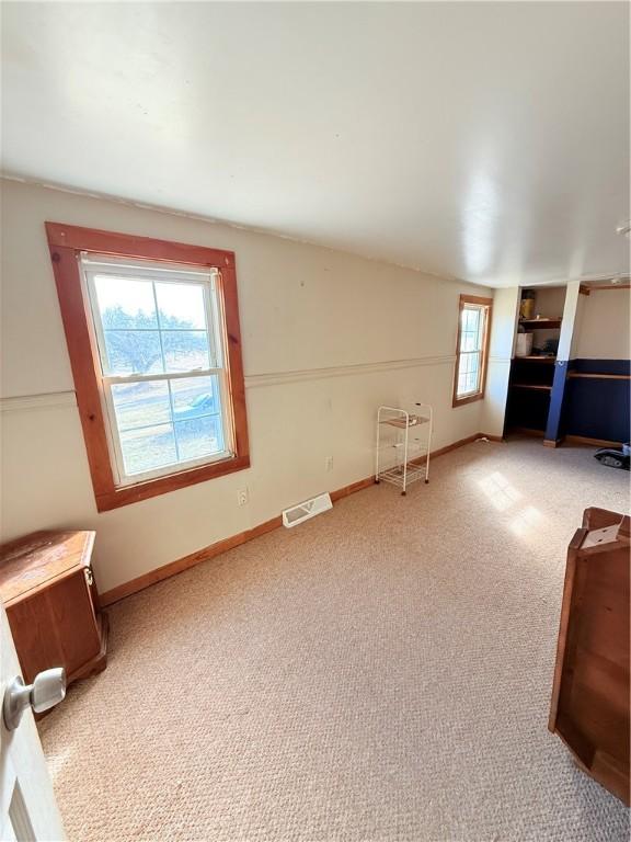 unfurnished living room with vaulted ceiling, carpet floors, visible vents, and baseboards