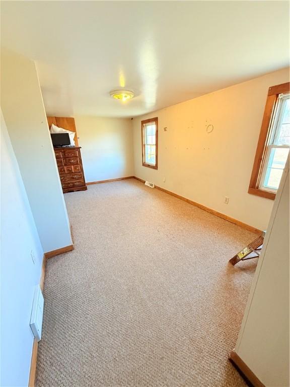 unfurnished living room with carpet flooring, visible vents, and baseboards