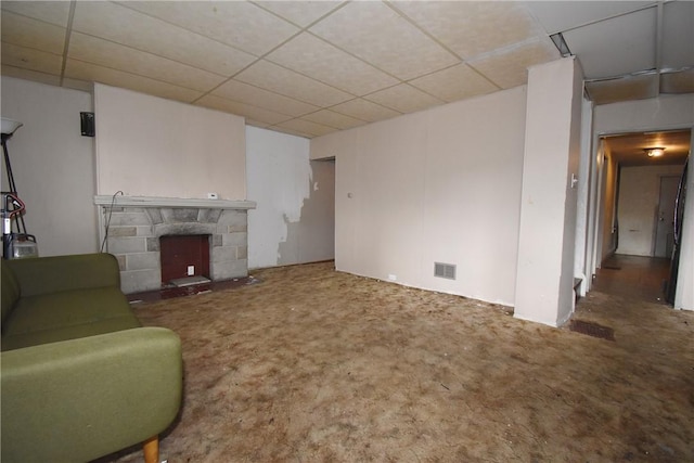 living area featuring a fireplace, visible vents, and a drop ceiling