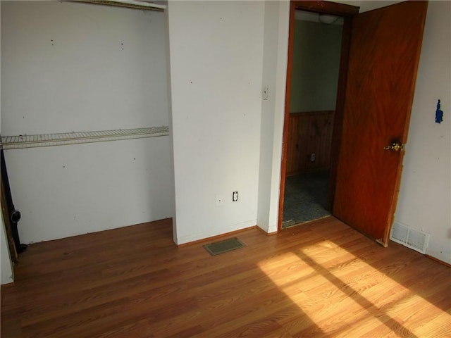 unfurnished bedroom featuring a closet, wood finished floors, and visible vents