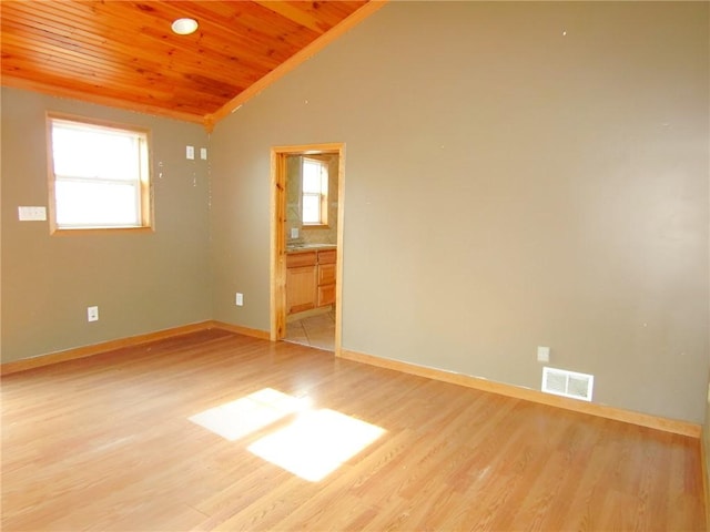 empty room with lofted ceiling, visible vents, plenty of natural light, and light wood finished floors