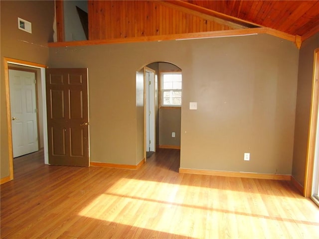 unfurnished room with lofted ceiling, arched walkways, wood finished floors, wood ceiling, and baseboards