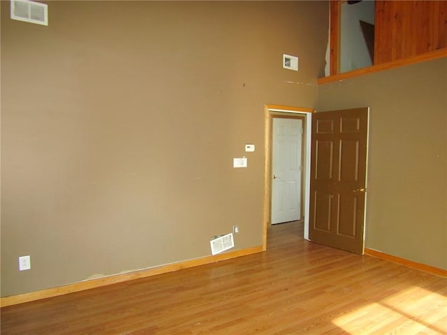 unfurnished room with wood finished floors, visible vents, and baseboards