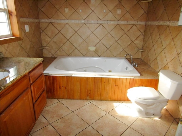 full bath with tile walls, toilet, vanity, a whirlpool tub, and tile patterned floors