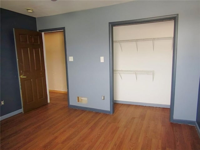 unfurnished bedroom with a closet, wood finished floors, and baseboards