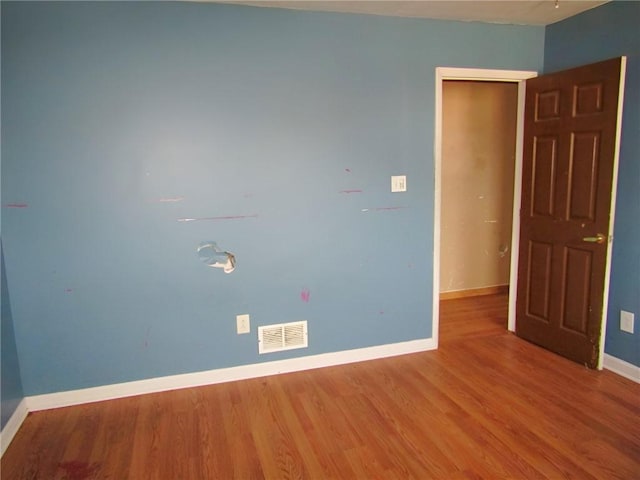 spare room featuring wood finished floors, visible vents, and baseboards