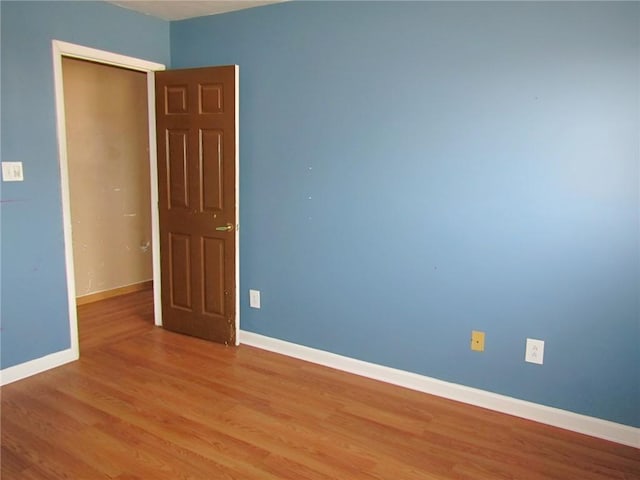 empty room featuring baseboards and light wood finished floors