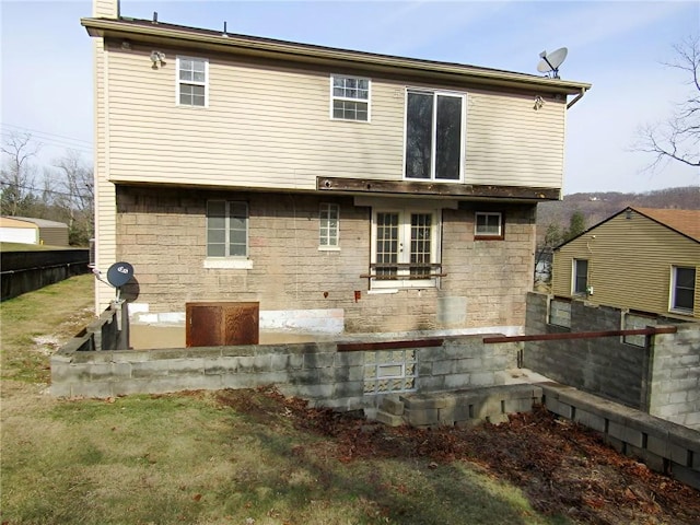 rear view of house featuring a chimney and fence