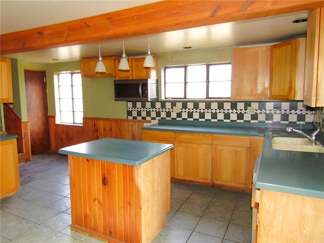 kitchen with light tile patterned flooring, a sink, wainscoting, a center island, and stainless steel microwave