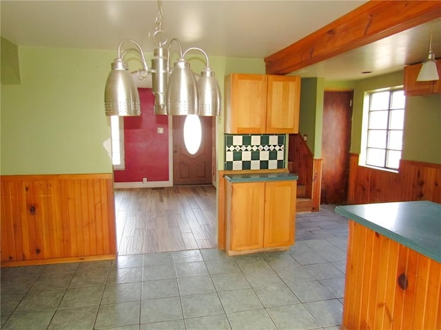 kitchen featuring wainscoting, beam ceiling, wood walls, a notable chandelier, and light tile patterned flooring