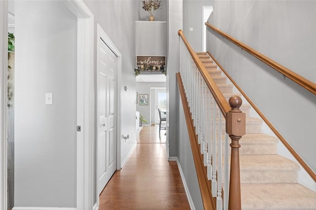 interior space with a towering ceiling, baseboards, and wood finished floors