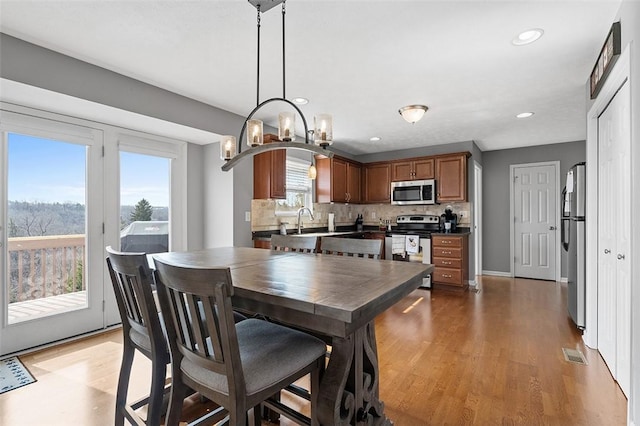 dining area featuring light wood finished floors, baseboards, arched walkways, a notable chandelier, and recessed lighting