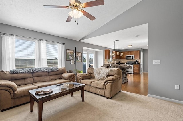 living area featuring lofted ceiling, baseboards, a wealth of natural light, and light colored carpet